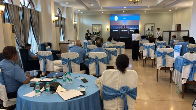 Hall laid out with blue-draped round tables and notepads as officers take their seats