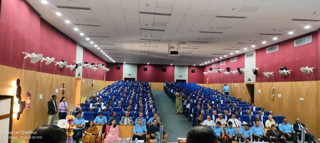 Wide view from the front of a packed auditorium of seated personnel and guests